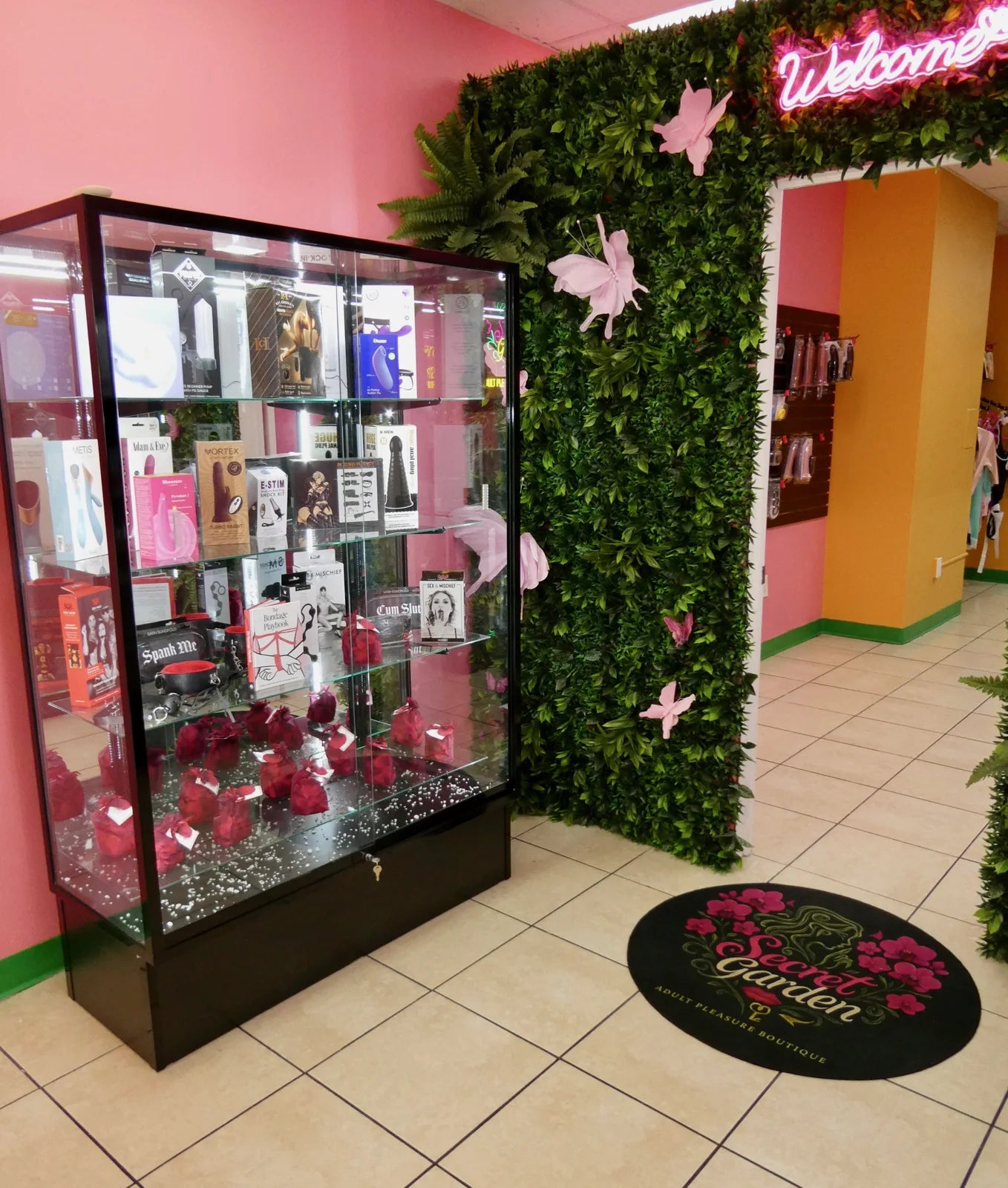 Secret Garden boutique welcome area with a green floral wall and glass display cabinet