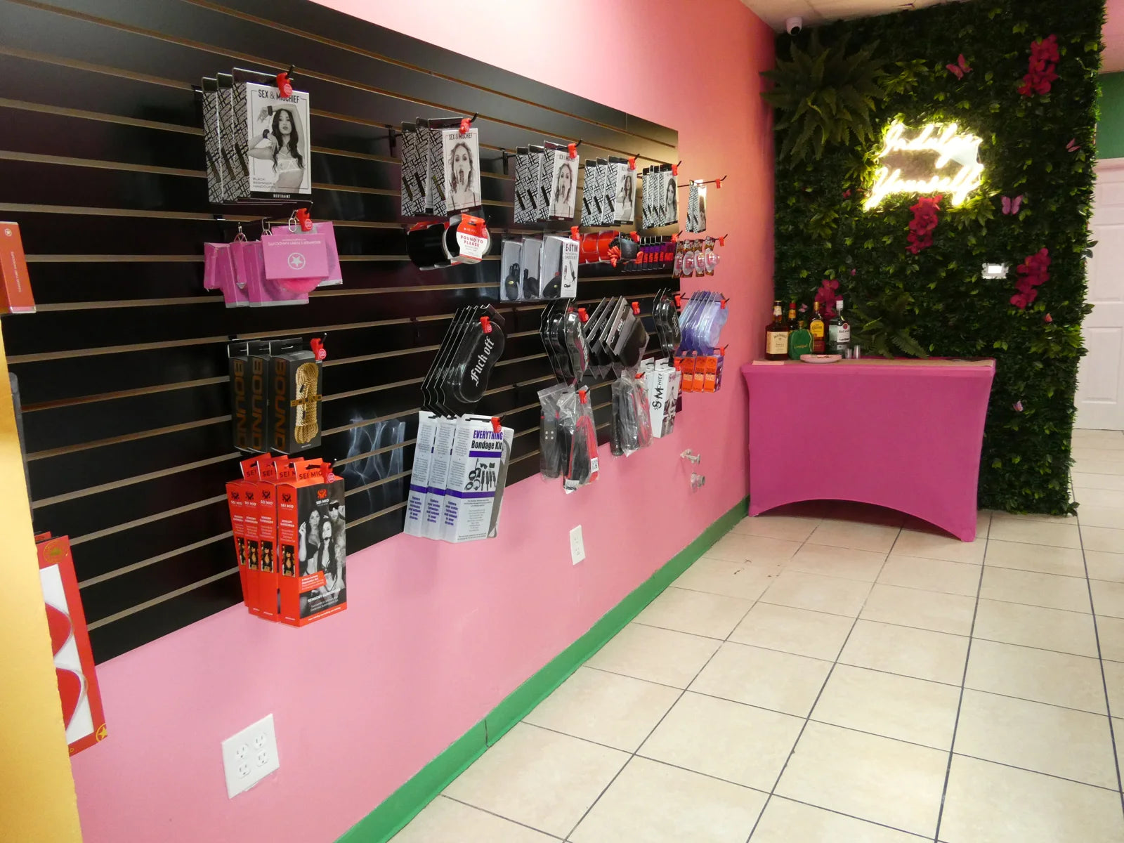 Pink boutique interior with accessories and a green floral feature wall